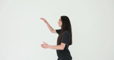 Gülümseyen genç kadın beyaz arka planda partneriyle dans ediyormuş gibi yapar. Mutlu kadın, stüdyoda tek başına vals yapma tekniğini geliştiriyor.