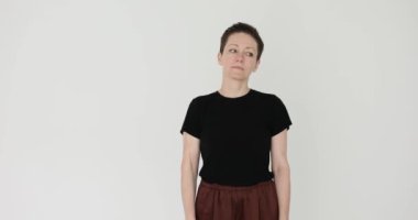 Odaklanmış kadın, boynu beyaz duvara yaslayarak baş eğme egzersizi yapıyor. Dişi, spor kulübünde vücudu ısıtan hareketleri dikkatle gerçekleştiriyor.