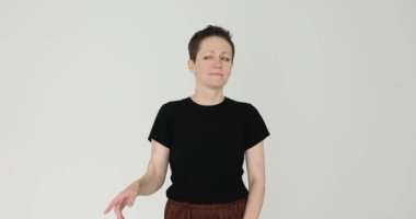 Kadın, işaret parmağıyla kafaya dokunarak dönüş hareketleri yapıyor. Dişilerin beyaz duvara karşı sorunlara çözüm bulmaya çalıştıklarını düşünüyorum.