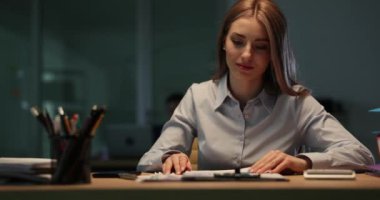 Kadın işçiler akıllı telefondan saatleri kontrol eden çizelgelerle raporları inceliyor. Kafası karışmış genç bir kadın gece geç saatlerde iş yerinde evrak işlerini yapar.