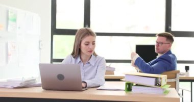 Erkek meslektaşım, ofis verilerini yavaş çekimde karşılaştıran belgeleri kadın yöneticiye gösteriyor. Şirket çalışanları iş yerlerinde birlikte evrak işleriyle uğraşırlar.