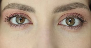 Temiz ciltli ve çıplak makyajlı genç bir kadın gözlerini yavaş çekimde kırpıyor. Çekici kadın doğal güzelliği minimum kozmetikle ön plana çıkarıyor