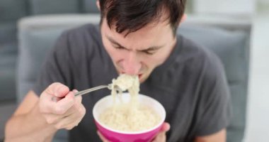 Adamın elinde restoranda lezzetli eriştelerle dolu bir kase var. Aç adam öğle arasında lezzetli yemekler yiyor. Yavaş çekim.