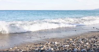 Kum ve kayalık kıyı manzarası. Gün batımında güzel bulutlu deniz manzarası ve bulanık hareket suyu