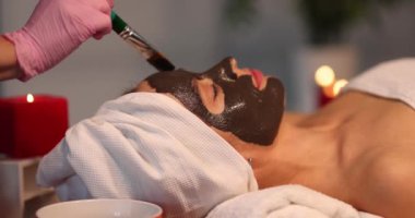 Genç kadın kuaförde yüzüne detoksifikasyon yapan kil maskeyi uyguluyor. Yüz bakımı ve gençleştirme konsepti