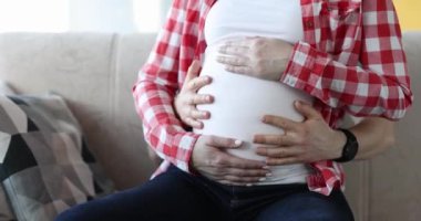 Koca, hamile karısının karnını okşuyor. Aile mutluluğu ve doğum kavramı