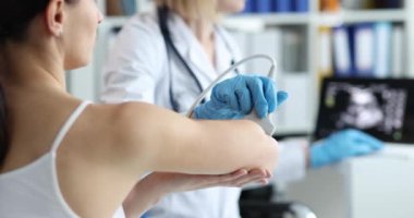 Doktor, klinikte hastanın dirseğini ultrasonla muayene ediyor. Romatoid eklem iltihabı semptomlara ve tedavi konseptine neden olur