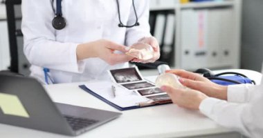Plastik cerrah klinikteki kadına silikon göğüs implantı gösteriyor. Göğüs büyütme ve kaldırma kavramı