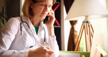 Klinikte telefonda konuşan gülümseyen güzel bayan doktor. Hastalara uzaktan danışma ve teletıp konsepti