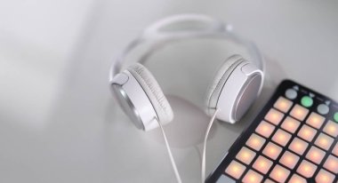 White headphones and beatbox on a gray background, close-up, blurry. A controller for making music. Simulating sounds