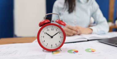 Ofisteki belgelerde kırmızı alarmlı saat, yakın plan, bulanık. Raporları gönderme, yönetimin etkinliğini kontrol etme zamanı