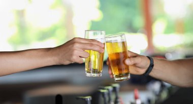 Bira bardakları olan erkek eller, yakın plan, bulanık. Bir barda rahatlamak, parti, bira tatmak.