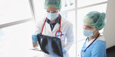 Klinikteki iki kadın doktor akciğerlerin röntgenine bakıyor, yakından. Zatürree teşhisi, viral hastalık, omikron.