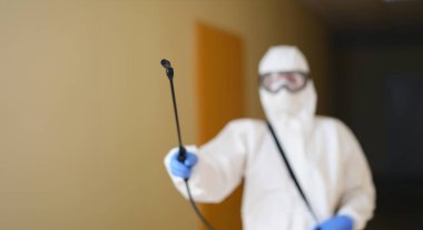 Disinfection specialist in protective uniform with a spray bottle, close-up, blurry. Deratization, deodorization service