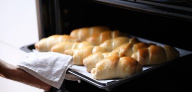 Open oven on a hot baking sheet, baked goods, close-up. Homemade croissants, puff pastry sausage, bun recipe