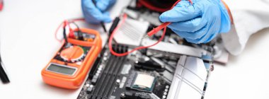 Hands in blue gloves to check electronic equipment with a multimeter, close-up. Repair, electrical troubleshooting, short circuit