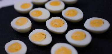 Set of halves of boiled chicken eggs on a black background, close-up. Chicken protein and yolk, organic food, keto diet