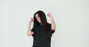 Gri arka planda yumuşak ritmik zarafetle dans eden bir kadın. Kadın hareketleri dramatik müzik ve doğal zamanlama ile derin bağlantıyı yansıtır