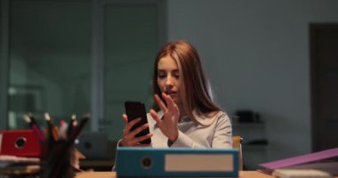 Bayan çalışanlar gece yarısı ofis konuşmalarının arasında telefonla konuşuyorlar. Bayan Yalnız Varlık ve odaklanmış davranış görevlere bağlılığı vurguluyor