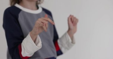 Liseli kız, beyaz arka planda bilek bükme egzersizi yapıyor. Kız, okul tatilinde ellerindeki gerginliği kolay bir egzersizle alıyor.