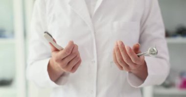 Kadın dişçi aletleri ve diş fırçasını elinde tutuyor. Kadın doktor, randevuda ağız sağlığı için önleme tedbirlerini açıkladı