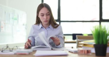 Şirket çalışanı, ofisteki iş yerinde oturan not defterindeki notları arıyor. Özenli genç kadın buluşmayla ilgili bilgi bulmaya çalışıyor.
