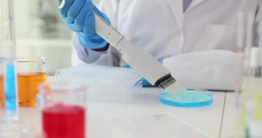 Laboratuvar çalışanı, iş yerindeki petri kabından çok kanallı pipetle sıvı topluyor. Üniformalı bilim adamı araştırmaya hazırlanan numuneleri döküyor.