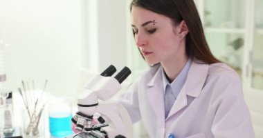 Araştırmacılar laboratuardaki modern mikroskobu kullanarak örnekleri inceliyor. Bilim adamı, optimal görünürlüğü sağlamak için büyütmede kesin düzenlemeler yapıyor.