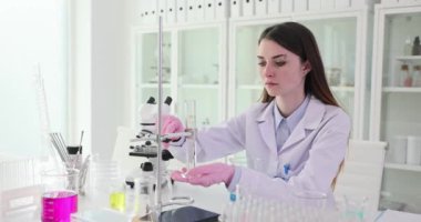 Kadın bilim adamı laboratuvarda uzun tüp yerleştirdi. Araştırmacı kesin ve güvenilir deneysel sonuçlar için ekipmanlara sıkıca bağlanır