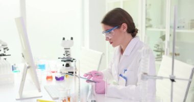 Kadın bilim adamı verileri bilgisayar ekranında gösterilen bilgilerle karşılaştırıyor. Gözlüklü kadın araştırmacı araştırmanın sonuçlarını hassasiyetle doğruladı