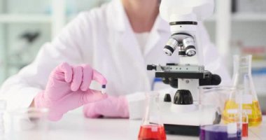 Kadın bilim adamı elinde mikroskopla hapları tutuyor. Kadın araştırmacı kapsül özelliklerini büyütme altında incelemeye hazırlanıyor