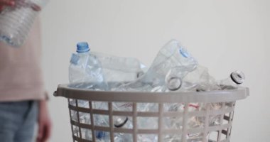 Kadın boş su şişesini yavaş çekimde çöp kutusuna atıyor. Tehlikeli doğa kirliliğini azaltmak için yeniden kullanılabilir plastik eşyalar toplanıyor