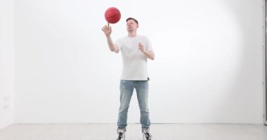 Gündelik giysiler içinde orta yaşlı bir adam ışık odasında parmak parmağında basketbol topu döndürüyor. Spor aletleri olan erkek trenler koridorda. Sağlıklı etkinlik