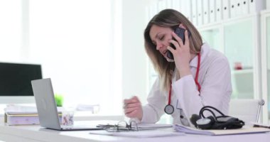 Doktor kadın hastaya danışmanlık yapıyor. İş yerinde telefonla konuşuyor. Formda cep telefonu işaretleme notları olan bir tıp uzmanı. Uzak atama