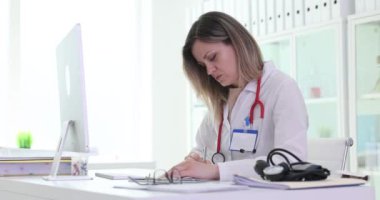Bilgisayarda hasta kayıtlarını dolduran pozitif kadın doktor tipleri. Tıp çalışanı klinikteki belgeleri kontrol etmek için bilgisayar üzerinde çalışıyor.