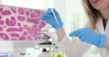 Kadın bilim adamı pipetle ilgileniyor. Tüpün içinde sıvı damlaları bırakıyor. Araştırmacıların deneylerde kesin ölçümler yapabilmek için detaylara olan dikkati çok önemlidir.