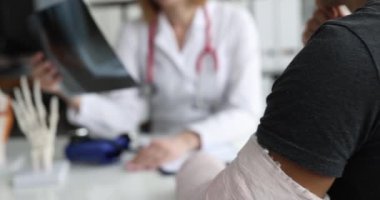 Doktor kırık kollu hastanın röntgenini inceliyor. Travmatolog ve kırık tedavisi konsepti