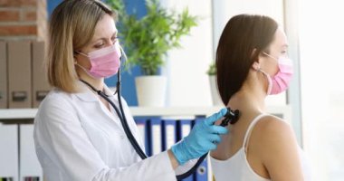 Doktor steteskopla hastayı dinler, kalp atışlarını ve akciğerlerini inceler. Pnömoni ve akciğer sorunu covid-19 salgını konseptinde