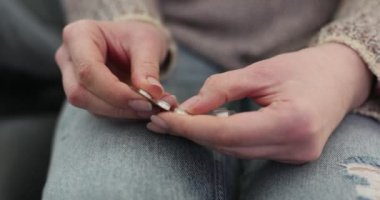 Genç kadın, su toplayan paketten hapları dikkatlice alıyor. Bayan parmaklarını nazikçe naylona bastırarak bir sonraki dozun tedavisini uygular.