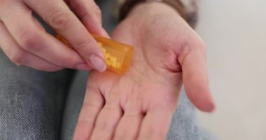 Genç bir kadın avucunun içine almak için bir avuç dolusu hap döker. Bayan belirtileri azaltmak için reçeteli doz almaya hazırlanıyor.