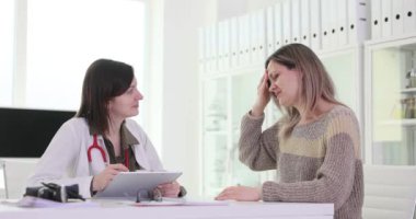 Kadın hasta kafasının arkasındaki ağrıyı açıklıyor. - Ne? Kadın, doktor için ağrı başlangıcı ve özellikleri hakkında bilgi verir.