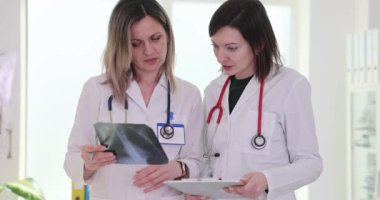 Bayan iş arkadaşları röntgen görüntülerini tartışmak için toplandılar. Doktorlar teşhis konusunda fikir birliğine varmak için detaylı paylaşım yorumlarını analiz ederler.