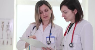 Bayan doktorlar gelecekteki tedaviler için hasta test sonuçlarını gözden geçiriyorlar. İşçiler, uygun eylem rotası üzerinde uzlaşmaya varmak için çeşitli faktörleri göz önünde bulundururlar