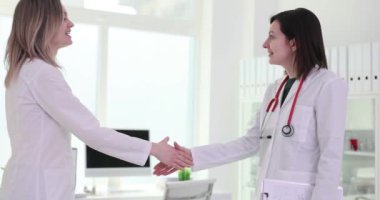 Kadın doktorlar işbirliğinin başlangıcı için el sıkışıyorlar. Gelecekteki projelerde birlikte çalışmaya karşılıklı saygı ve ortak kararlılık