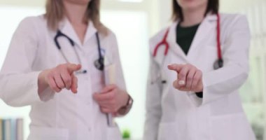 Beyaz önlüklü kadın doktorlar işaret parmağıyla işaret ediyor. Kadınlar bir sonraki mücadeleye hazır olduklarının ya da önemli meselelere doğrudan ilgi gösterdiklerinin sinyallerini veriyor