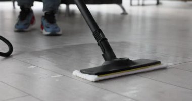 Adam kiri temizlemek için zemini delmek için paspas kullanıyor. İnatçı kirle mücadelede ve hijyenik çevreyi sağlamada modern cihaz etkinliği