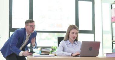 Dizüstü bilgisayarda çalışan kadın işçiler ve şirket ofisinde ekran fotoğraflarını çeken erkekler. Meslektaşının kariyerinde ilerlemek için haksız davranışları