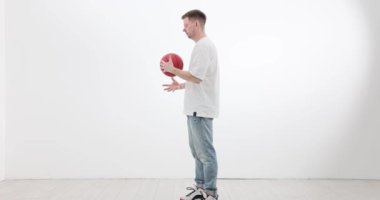 Erkek sporcu basketbol topunu yavaş çekimde yavaşça tutuyor. Sporcu, oyunda başarı için koordinasyonu geliştiren egzersizler yapar