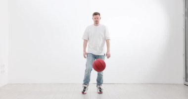 Erkek sporcu basketbol topunu geniş bir spor salonunda ağır çekimde yakalıyor. Sporcu, yarışmada başarı kazanmak için teknik performans egzersizini geliştiriyor.