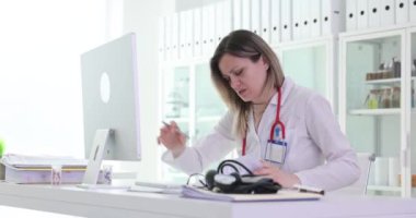 Kadın doktor bilgisayar ekranındaki verileri karşılaştıran belgeleri kontrol ediyor. Steteskopla kafası karışmış kadın doktor, hastanedeki işyerinde hata olduğunu fark etti.